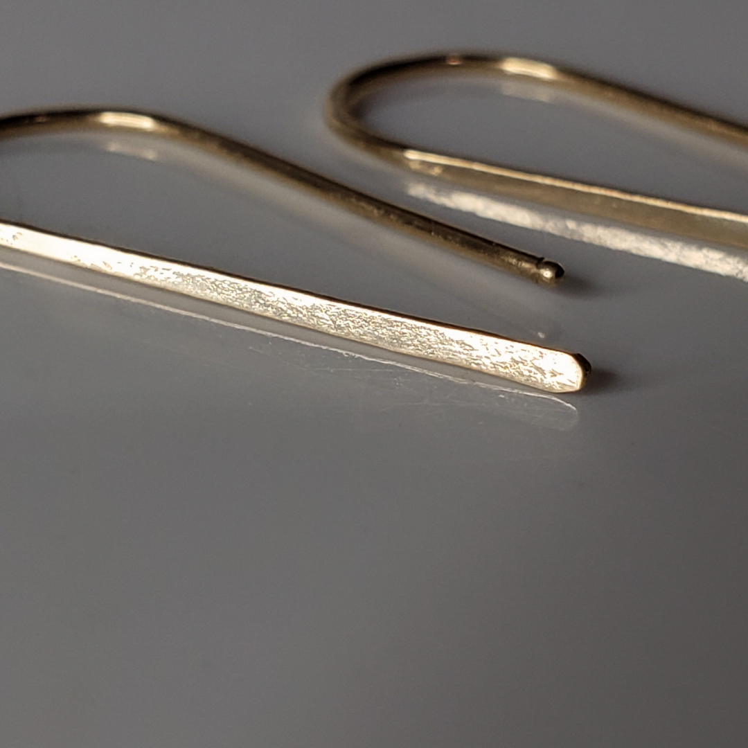 Small 14k gold threader earrings against white background