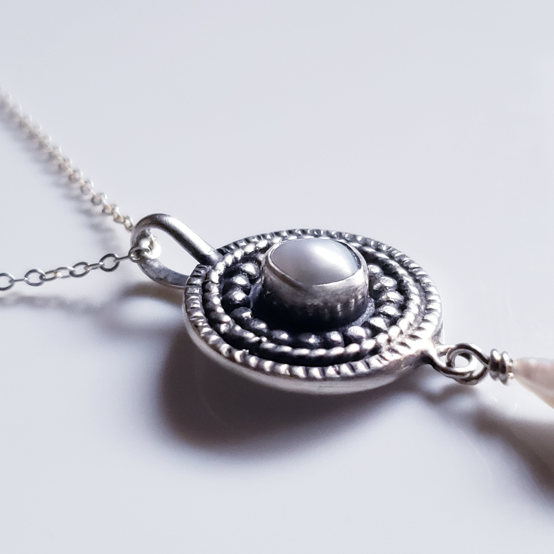 Silver and pearl mandala necklace against a white background