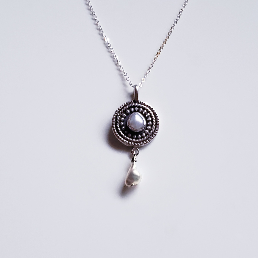 Silver and pearl mandala necklace against a white background