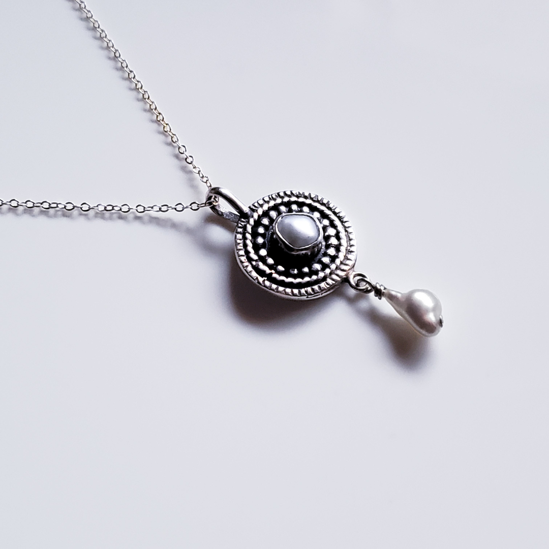 Silver and pearl mandala necklace against a white background