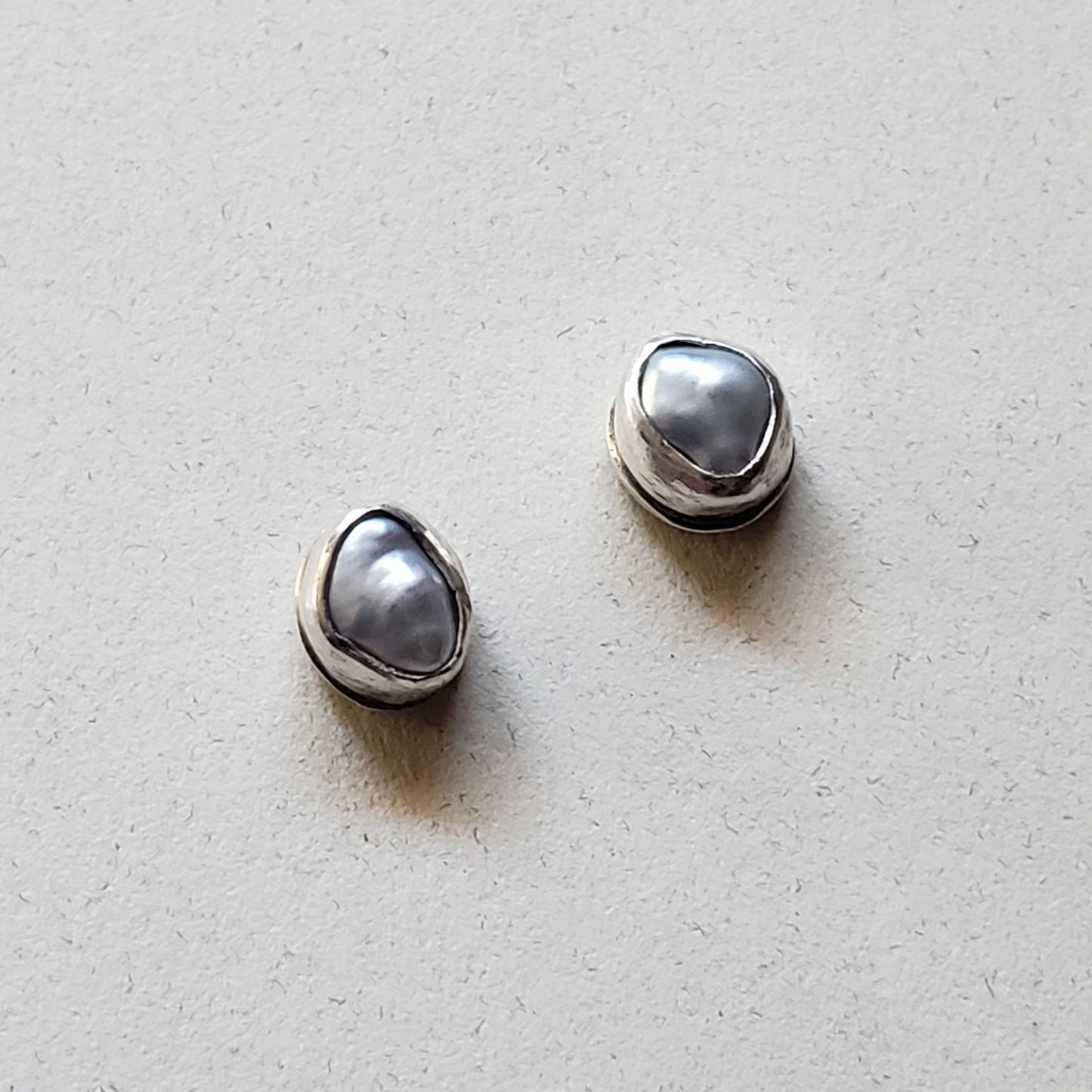 Organic pearl stud earrings on beige background