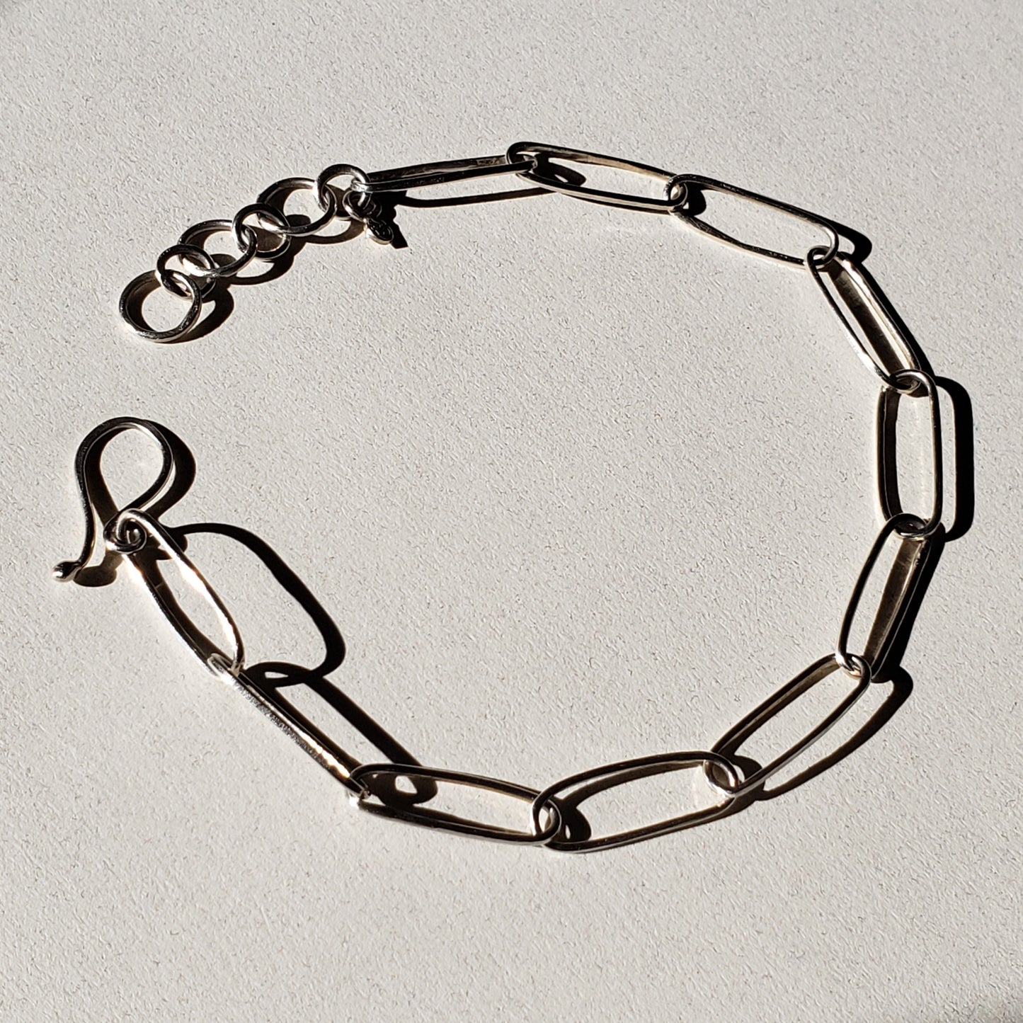 Adjustable silver link bracelet against beige background