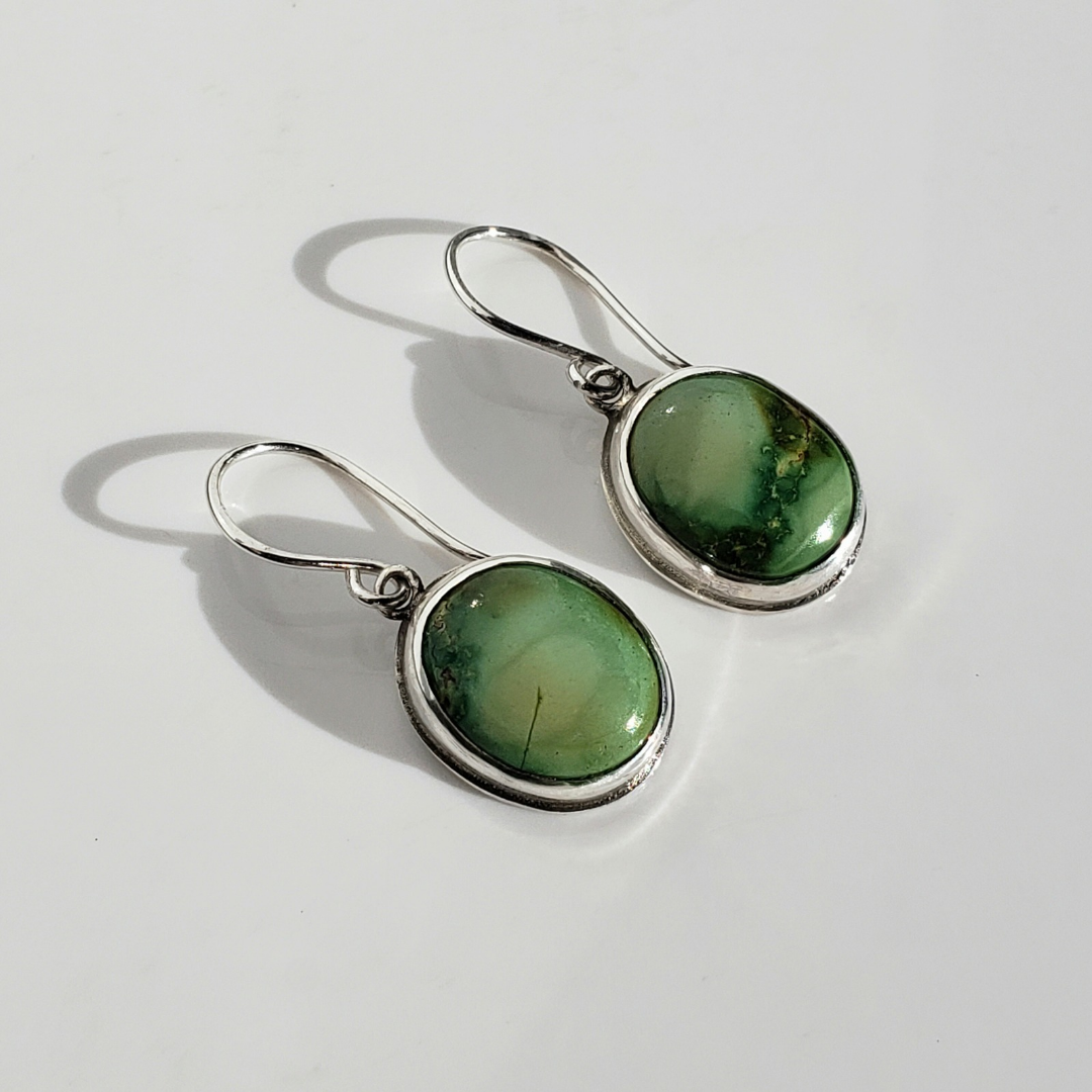 This is a image of a pair of green oval turquoise earrings on white background for display