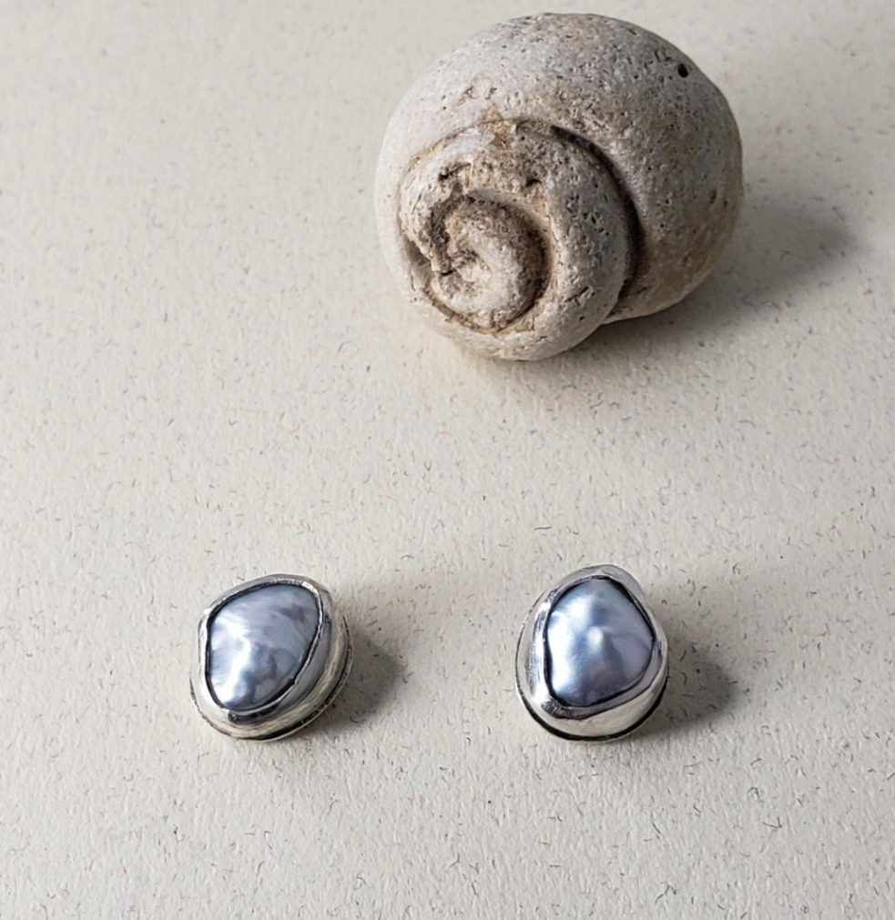 Organic pearl stud earrings against beige background