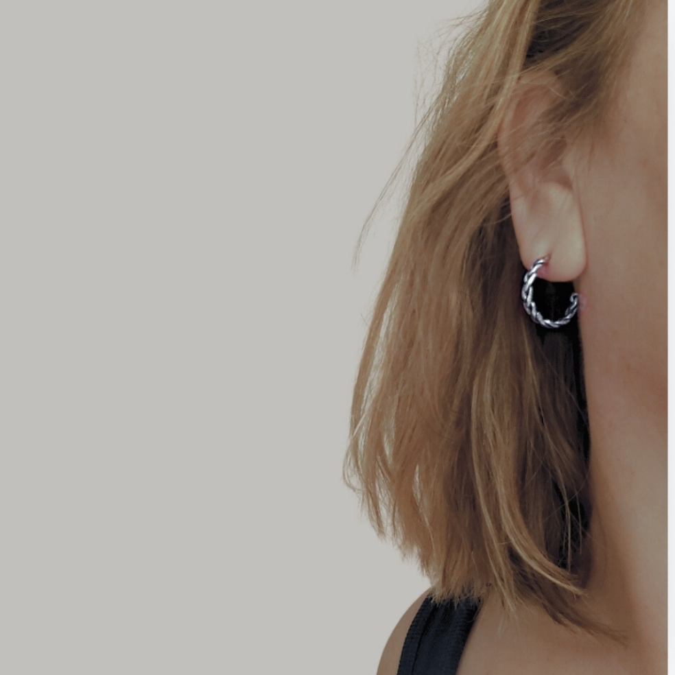 A pair of handcrafted silver hoop earrings on a blonde model