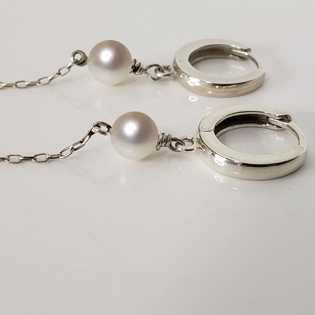Sterling silver hoop earrings with pearl drop against white background