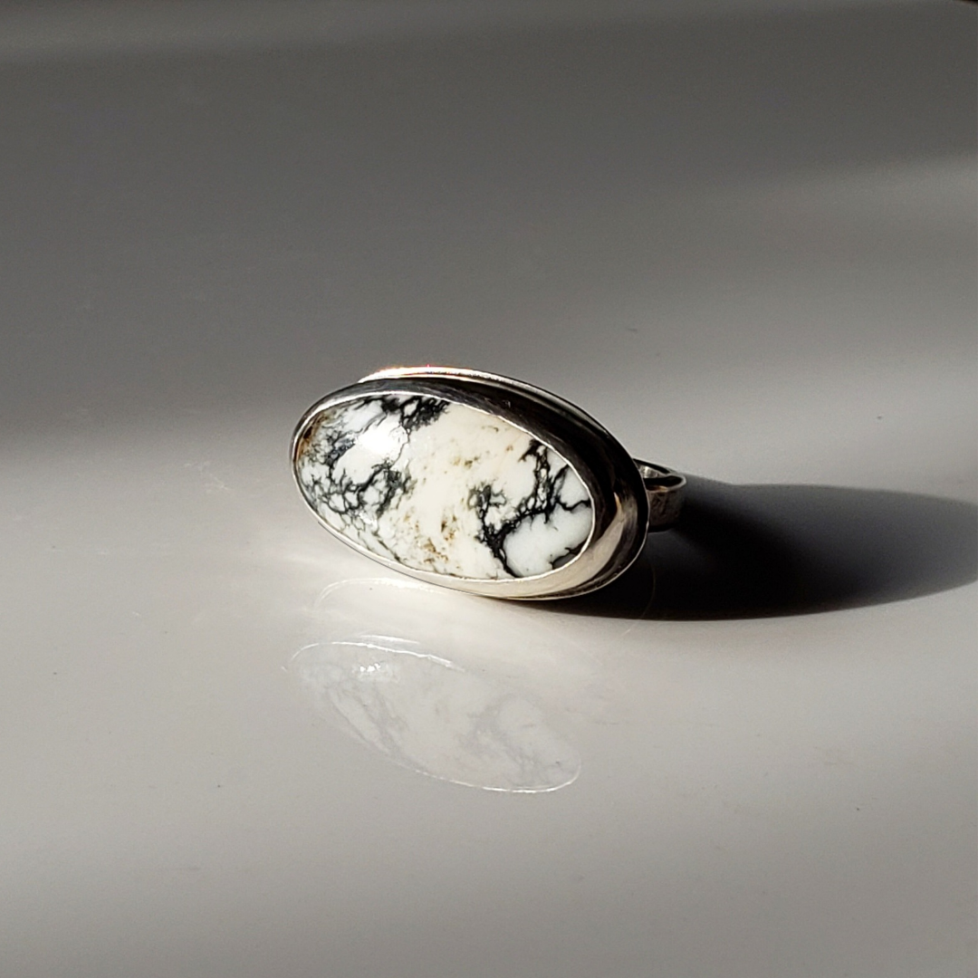 White Buffalo gemstone ring against gray background