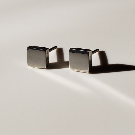 Small handcrafted sterling silver square stud earrings against white background.