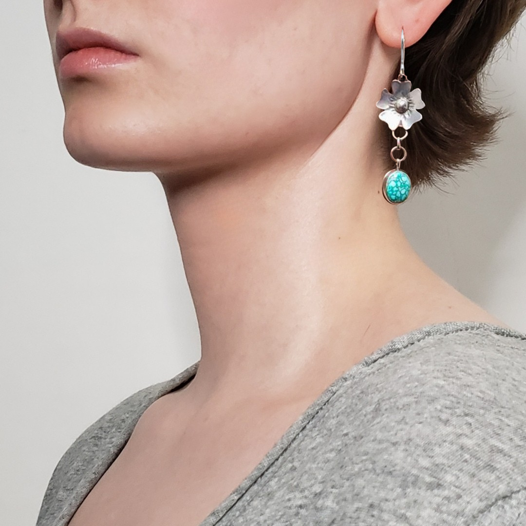 Left facing woman wearing large silver flower earrings
