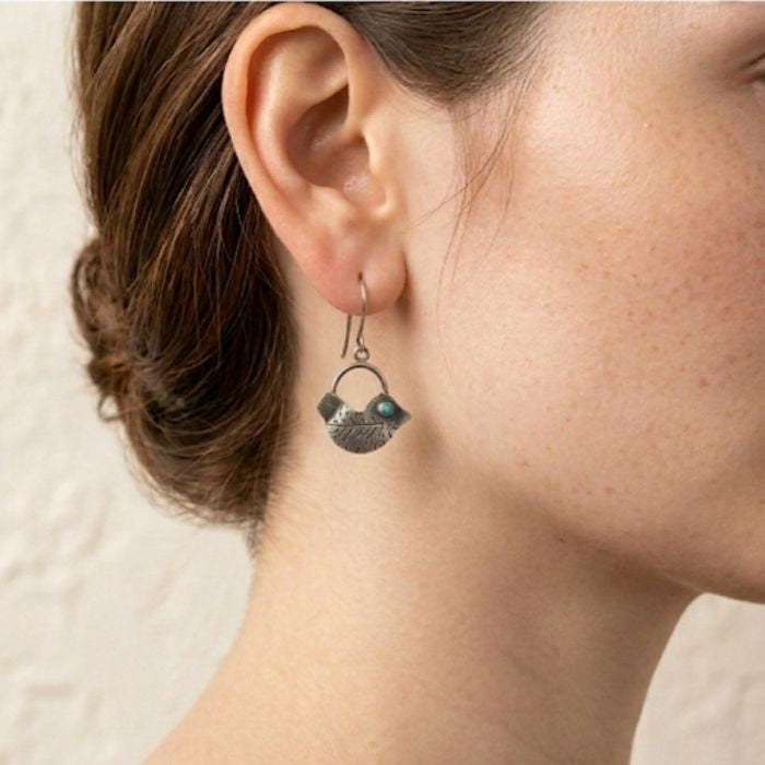 Close-up of a person wearing a unique earring with a neutral background