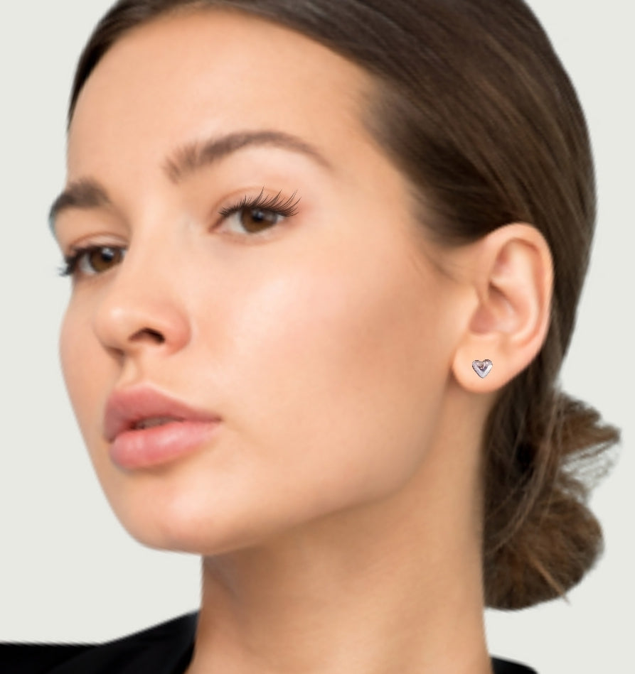 Left facing model wearing small silver heart earrings