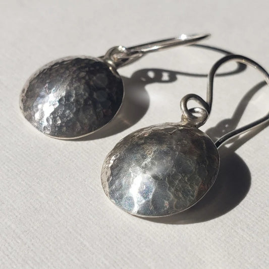 Small silver disc earrings with hammered texture hung from handmade artisan wires
