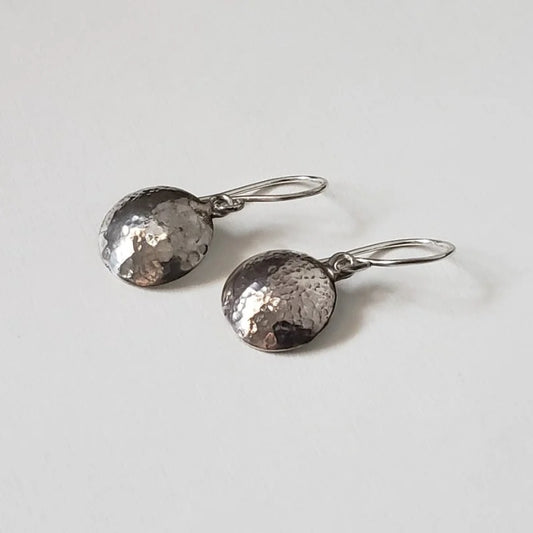 Small silver disc earrings with hammered texture hung from handmade artisan wires