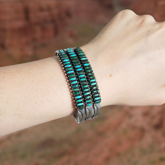Bracelet with turquoise stones on a wrist against a blurred natural background