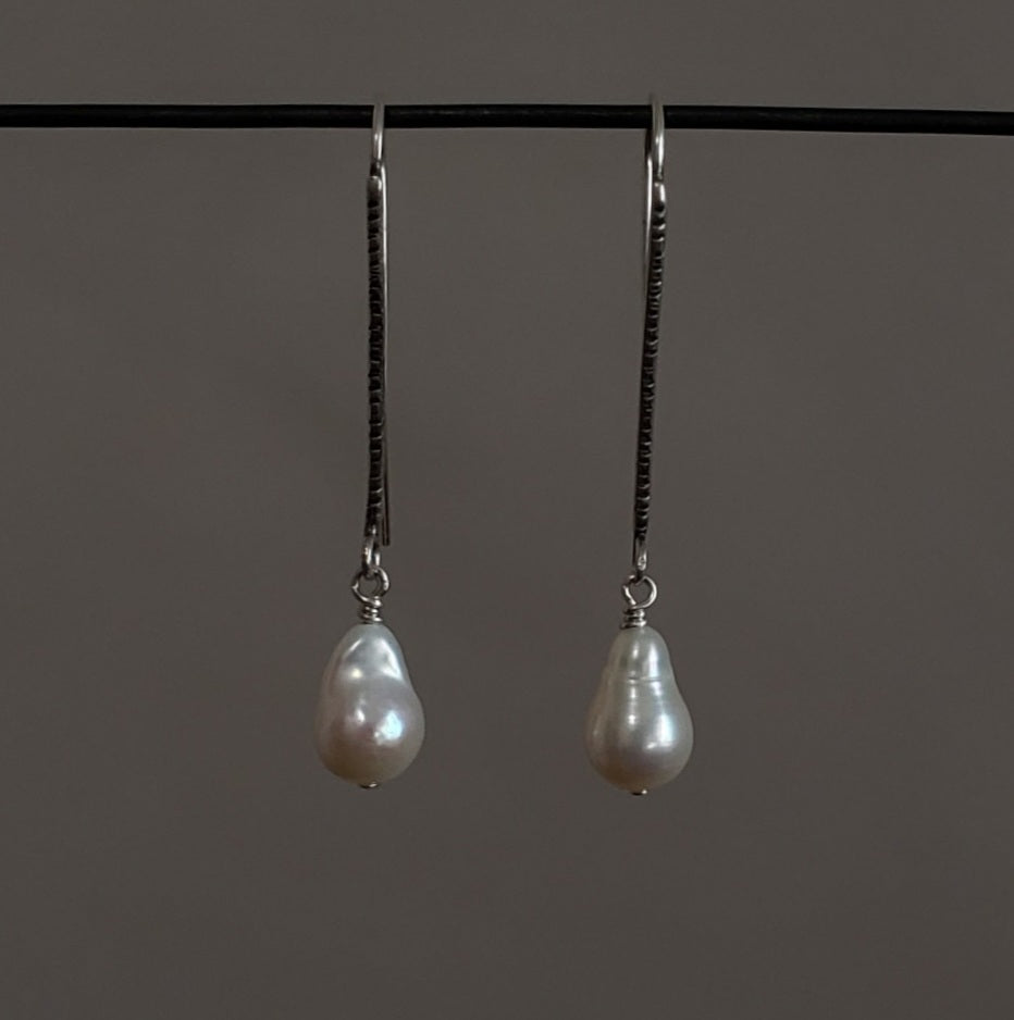 Long baroque pearl earrings hanging on a sterling silver ear wire
