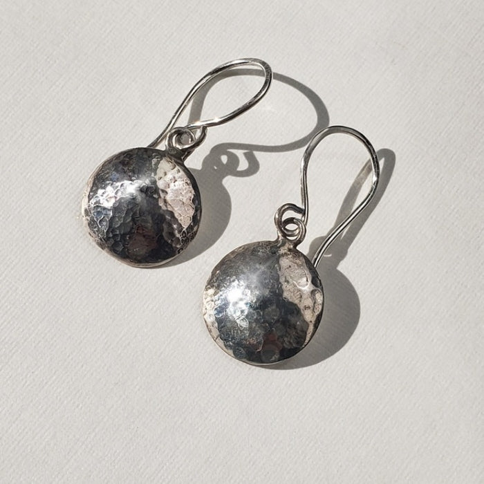 Small silver disc earrings with hammered texture hung from handmade artisan wires