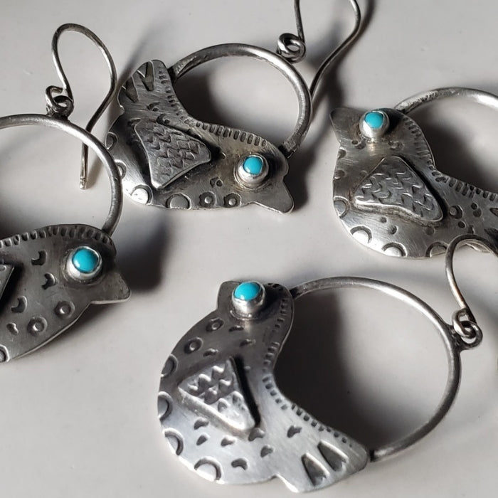 Silver earrings with turquoise stones on a light gray background