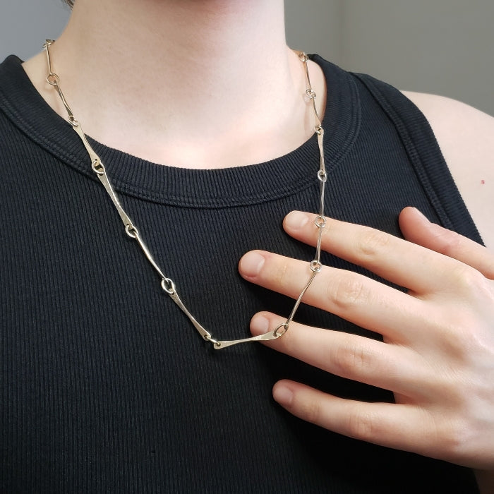 Image of woman holding large silver bone chain across fingers
