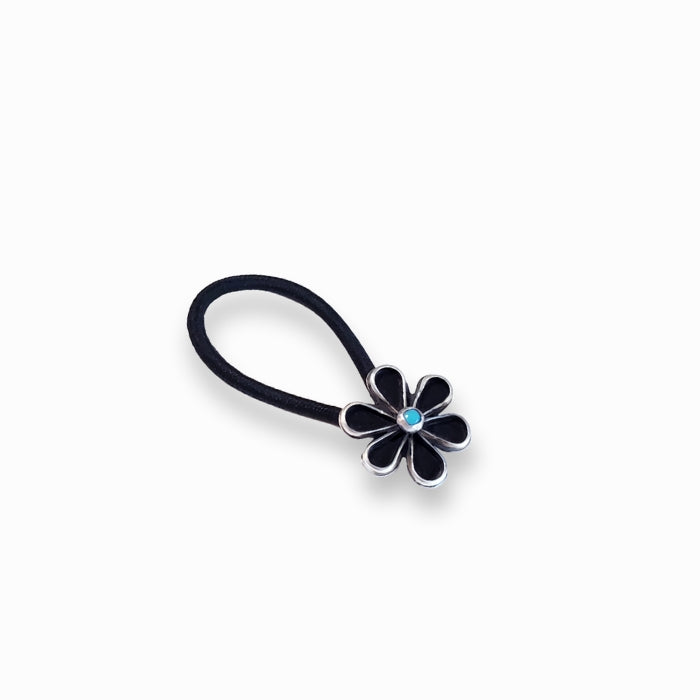 sterling silver daisy flower with turquoise center attached to a black hair tie.