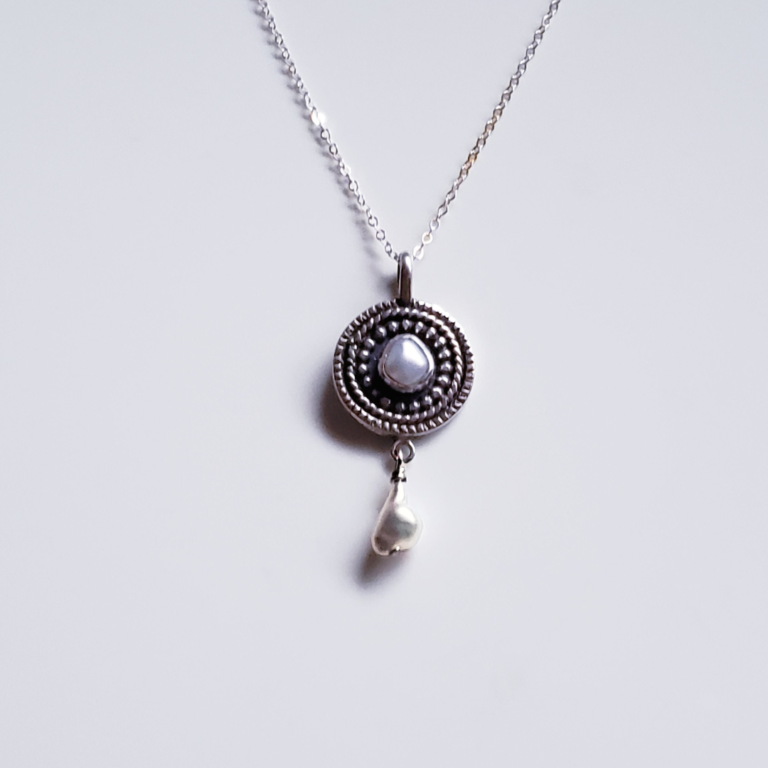 Silver and pearl mandala necklace against a white background 