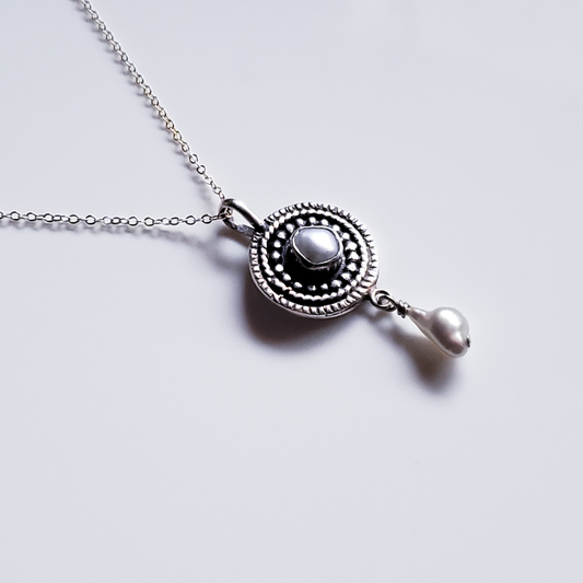 Silver and pearl mandala necklace against a white background 