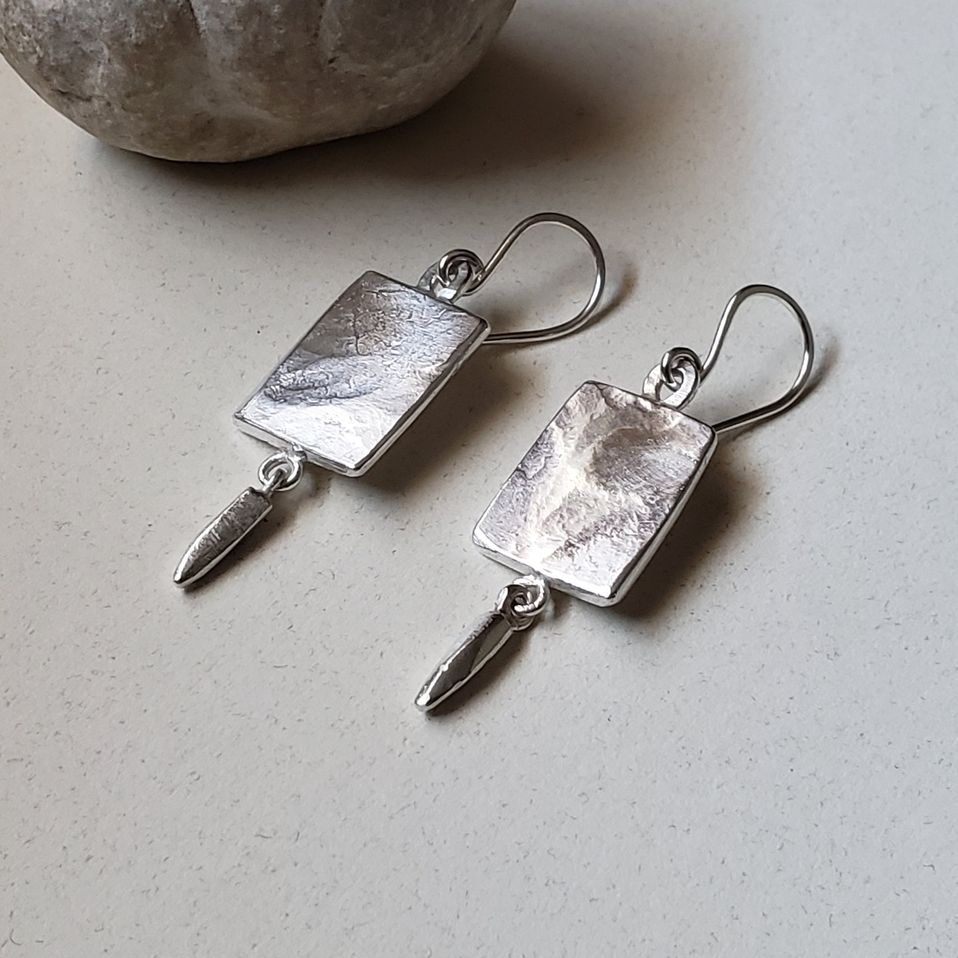 Thick sterling silver rectangle earrings left facing on gray background 