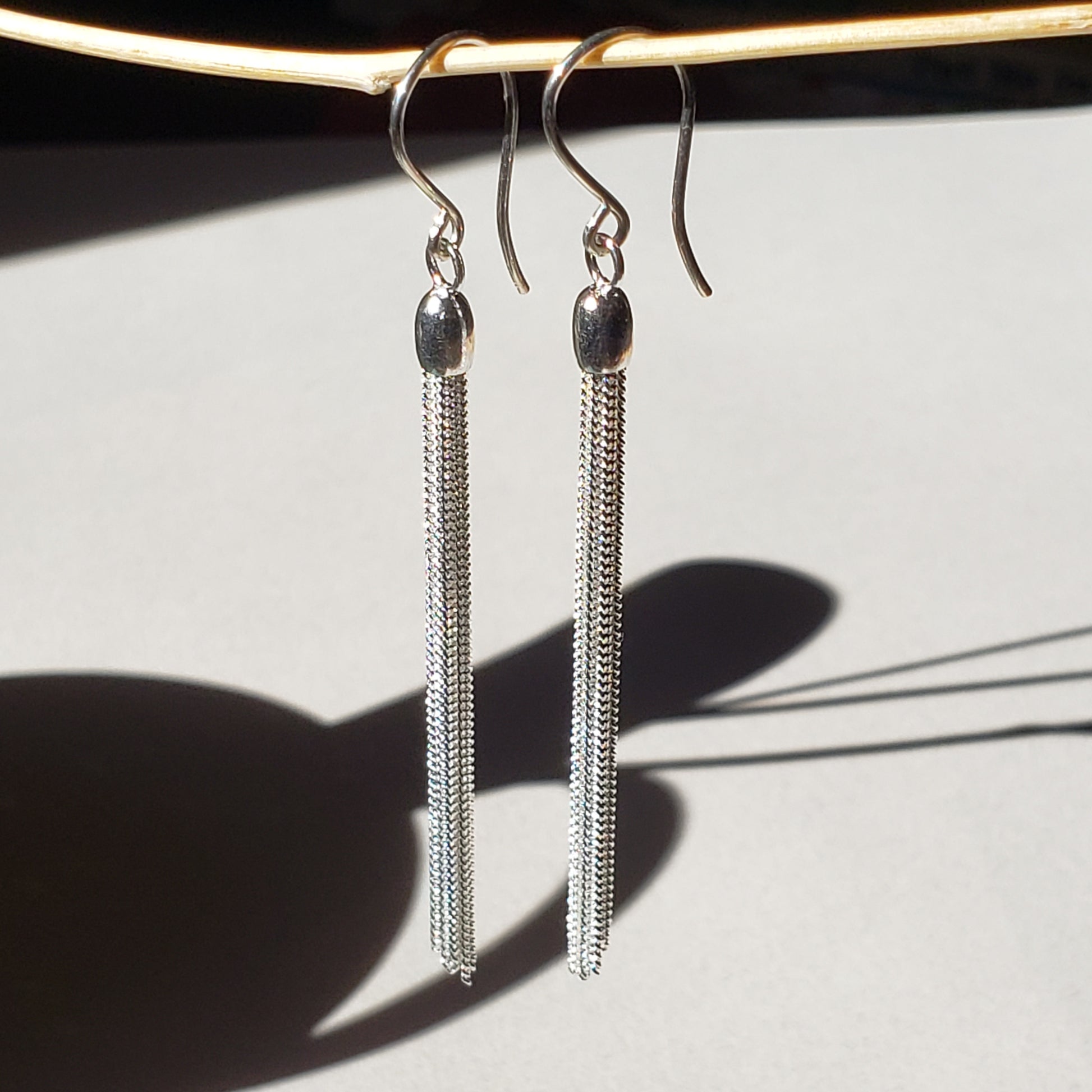 This is an image of long silver chain dangles earrings made by Jennifer Favour jewelry. These long silver earrings are lightweight and have 8 chain dangles hung from handmade sterling silver wires. These silver fringe earrings are 100% sterling silver, 3" total length. Ready to ship. 