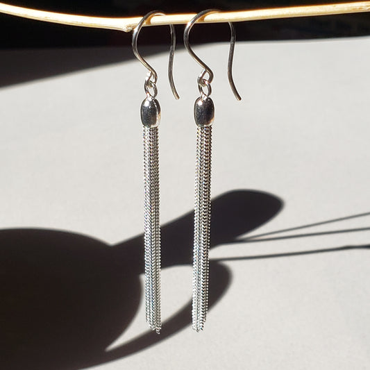 This is an image of long silver chain dangles earrings made by Jennifer Favour jewelry. These long silver earrings are lightweight and have 8 chain dangles hung from handmade sterling silver wires. These silver fringe earrings are 100% sterling silver, 3" total length. Ready to ship. 