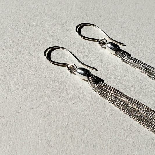 This is an image of long silver chain dangles earrings made by Jennifer Favour jewelry. These long silver earrings are lightweight and have 8 chain dangles hung from handmade sterling silver wires. 100% sterling silver, 3" total length. Ready to ship.