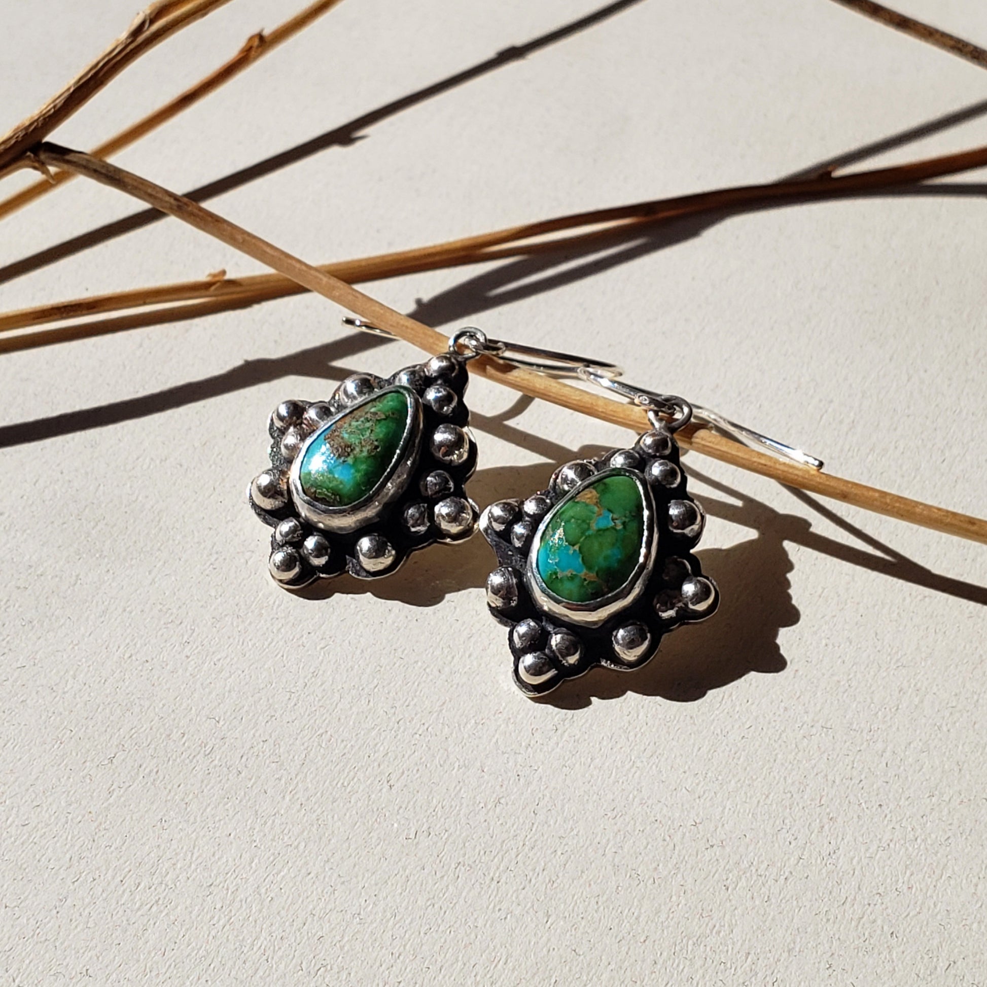 Beautiful blue and green teardrop turquoise stones set in a smooth silver bezel setting and surrounded by small sterling silver spheres. These handmade turquoise earrings are unique and easy to wear. They are hung from handmade sterling silver wires. 