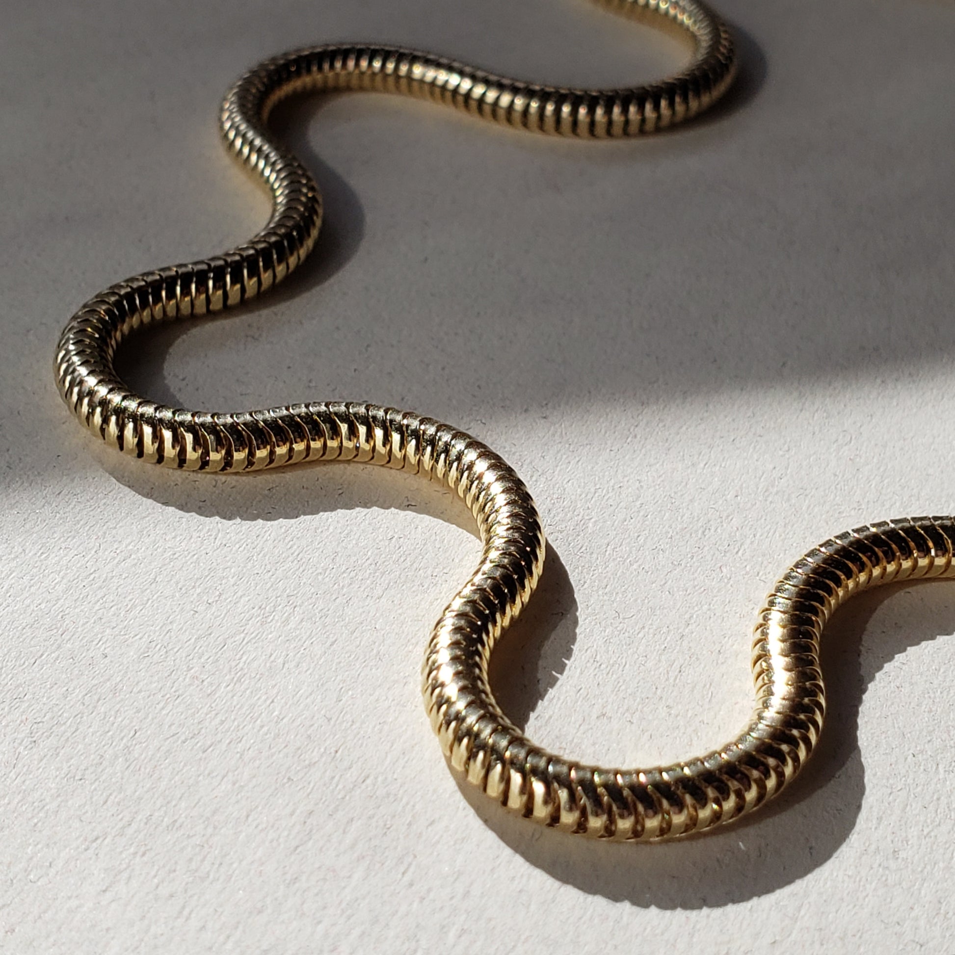 This is an image of a thick gold snake chain necklace. This gold snake chain measures 18" end to end and is 3mm thick. This gold chain has a textured appeal and will wear beautifully for year to come. 