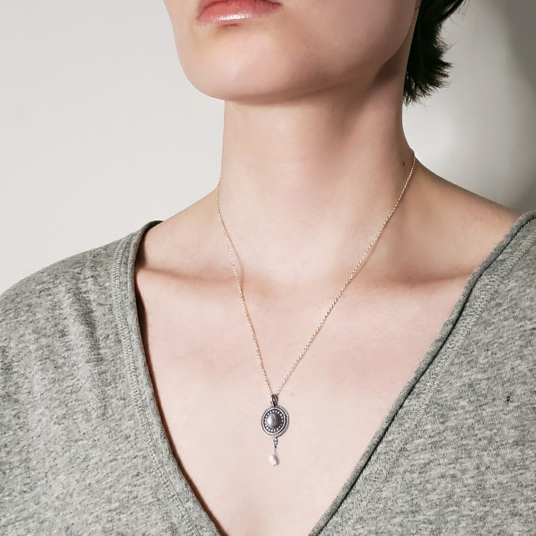 Model wearing a silver and pearl mandala necklace against a white background 