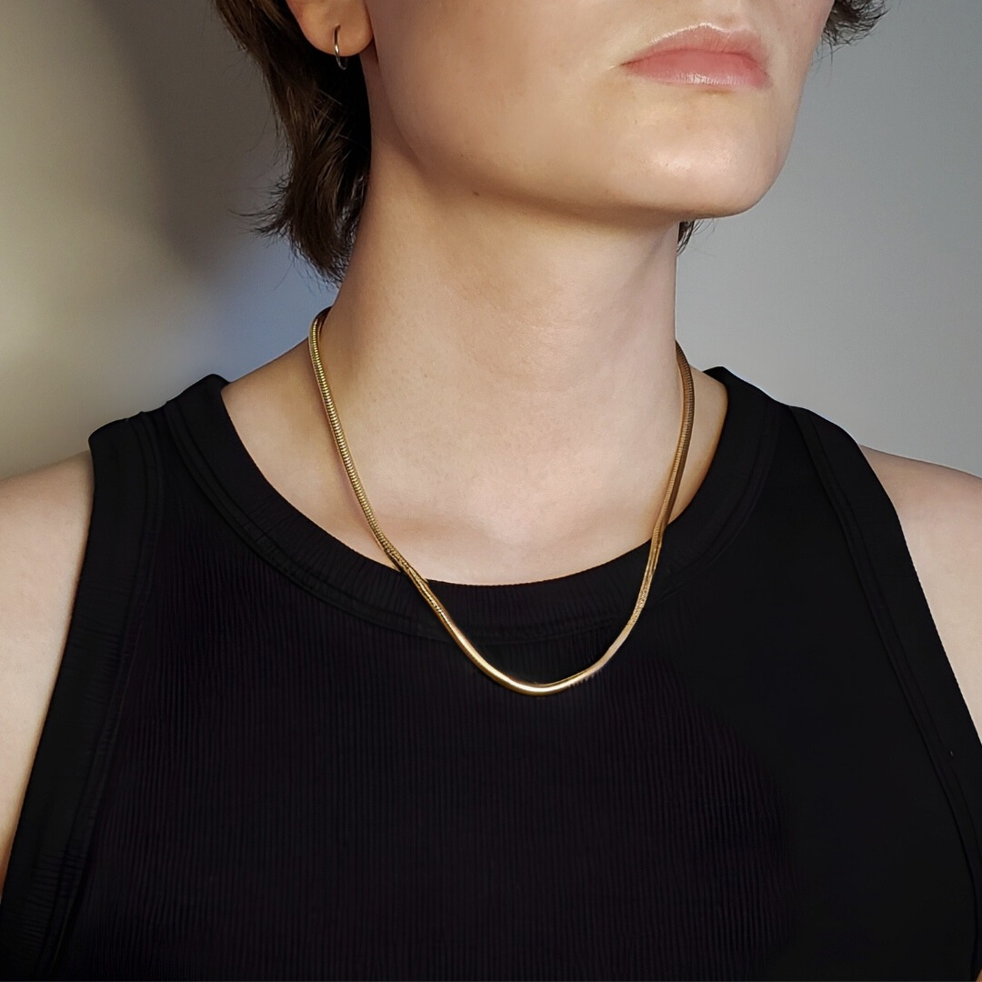 Image of model wearing thick gold snake chain necklace 