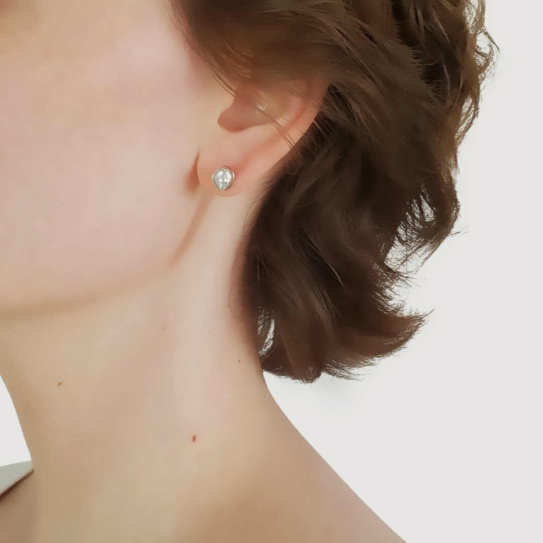 Image of model head profile left facing wearing small pearl stud earrings in sterling silver 