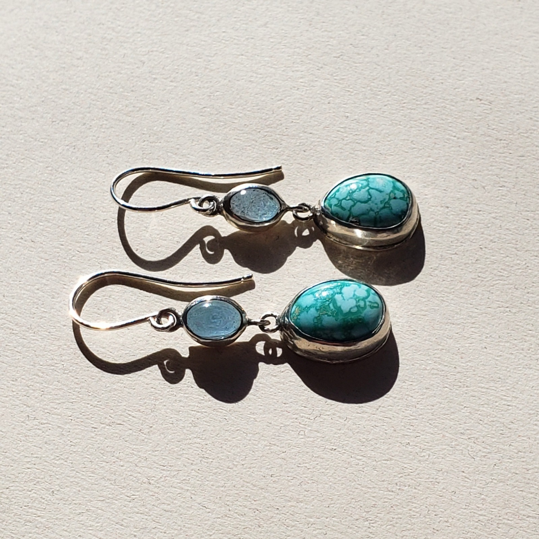 A left facing image of turquoise and silver artisan earrings