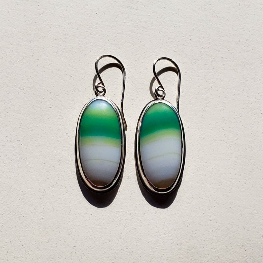 Image of flat lay green onyx earrings with striped stones in sterling silver on white background