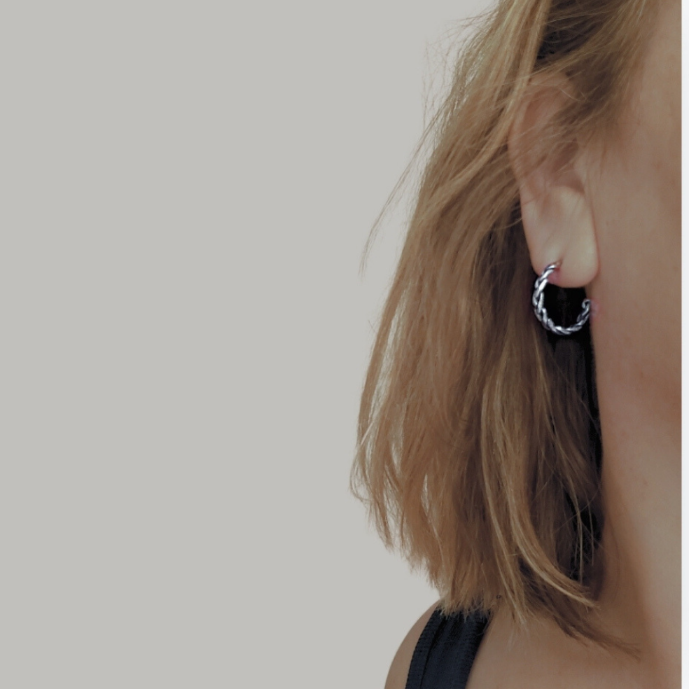 A pair of handcrafted silver hoop earrings on a blonde model 