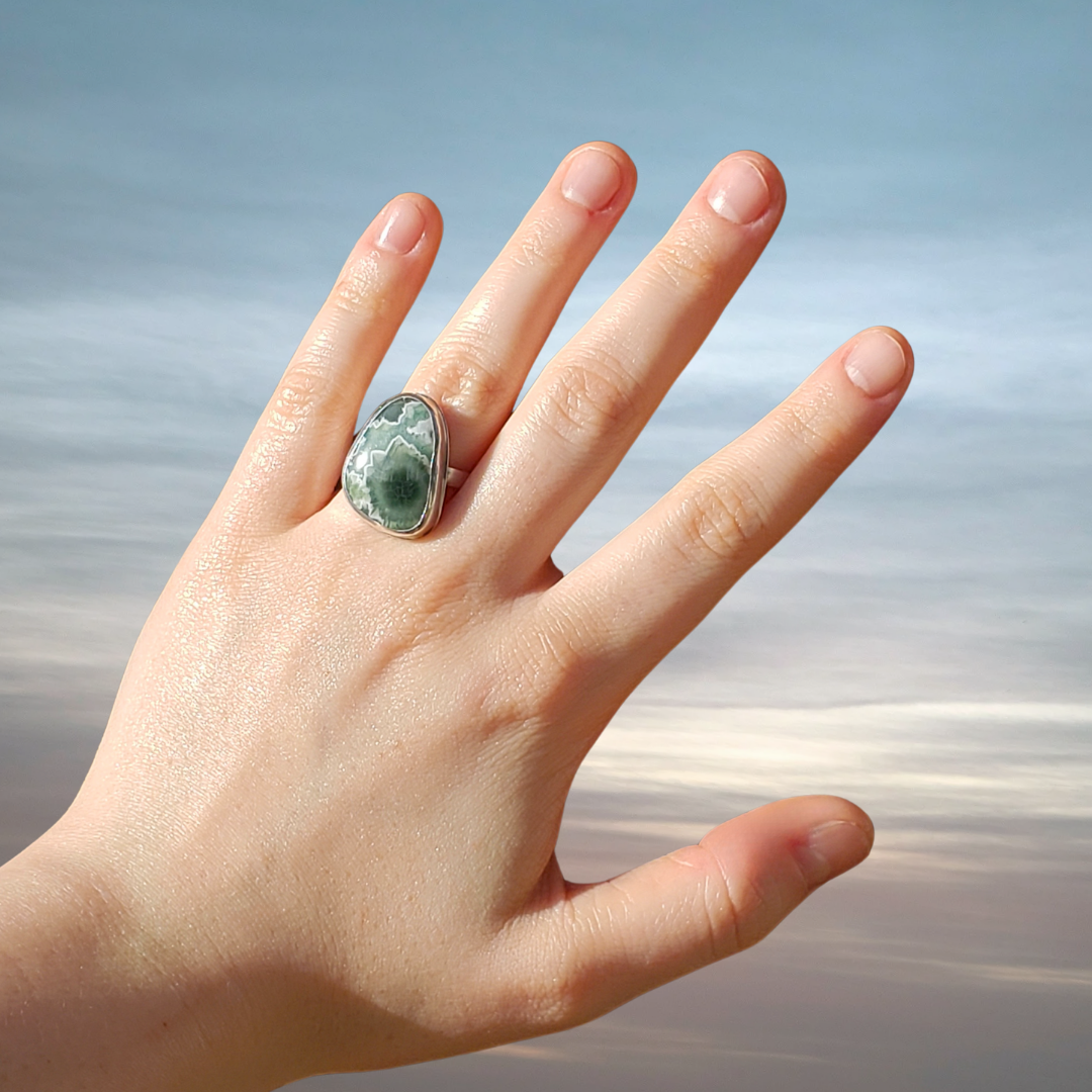 Large gemstone ring on hand with cloud background 