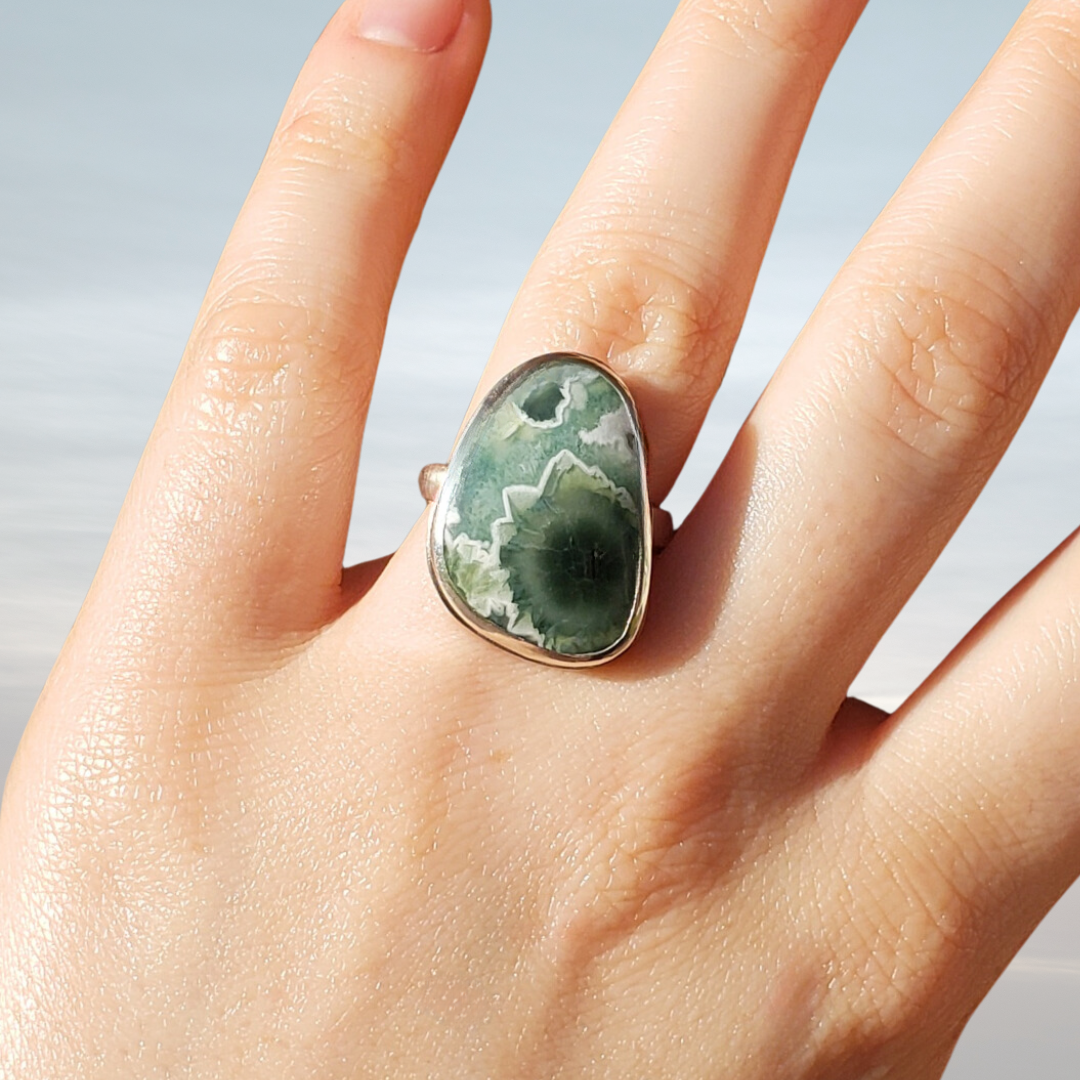 Large gemstone ring on hand against brown background 