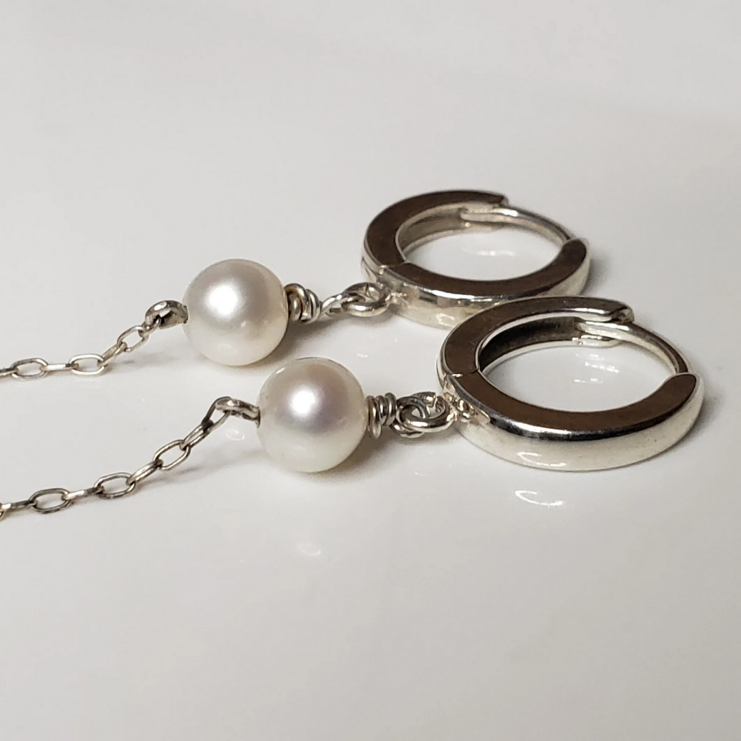 Sterling silver hoop earrings with pearl drop against white background