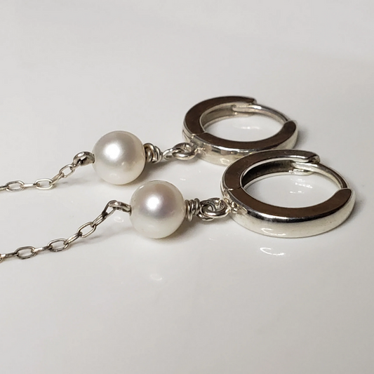 Sterling silver hoop earrings with pearl drop against white background