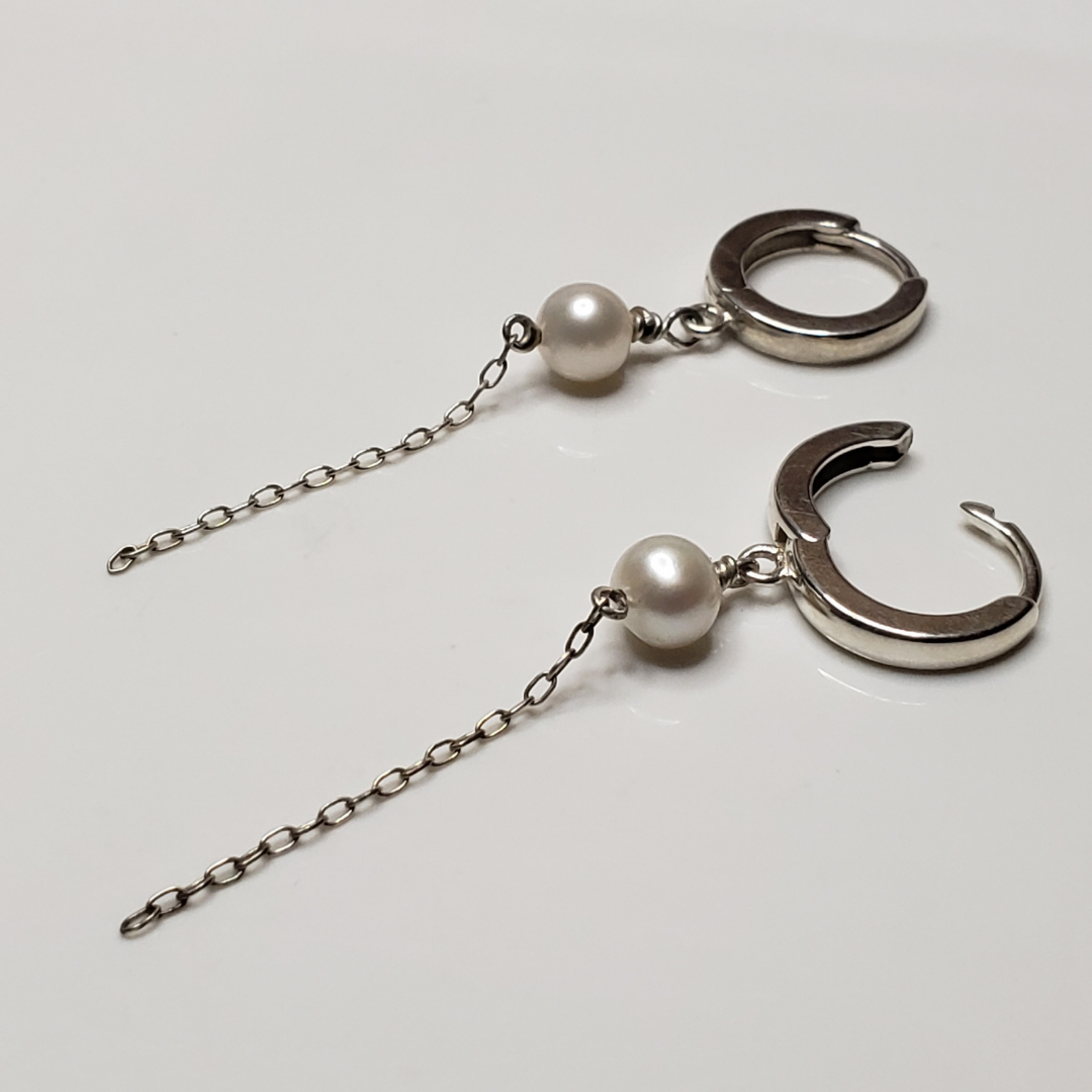 Sterling silver hoop earrings with pearl drop against white background