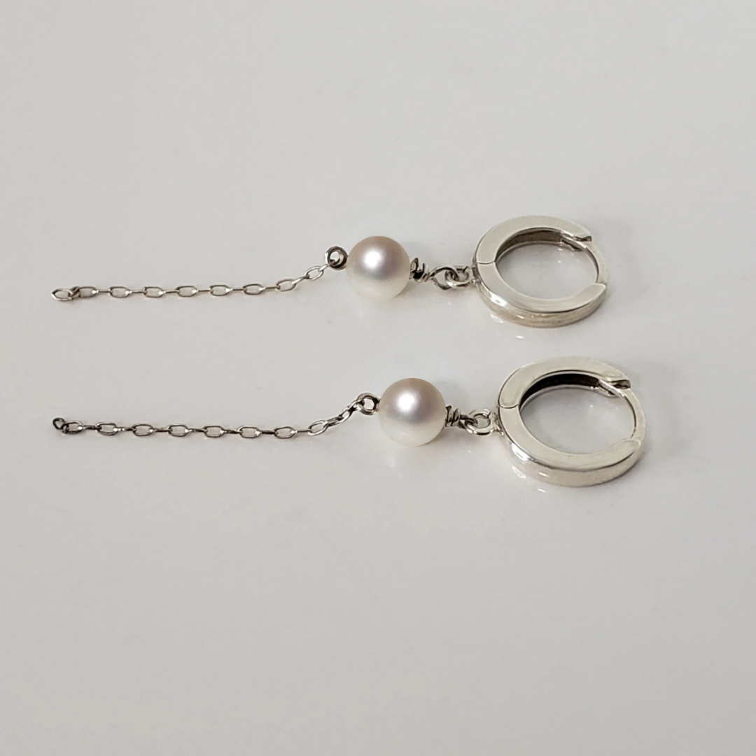 Sterling silver hoop earrings with pearl drop against white background