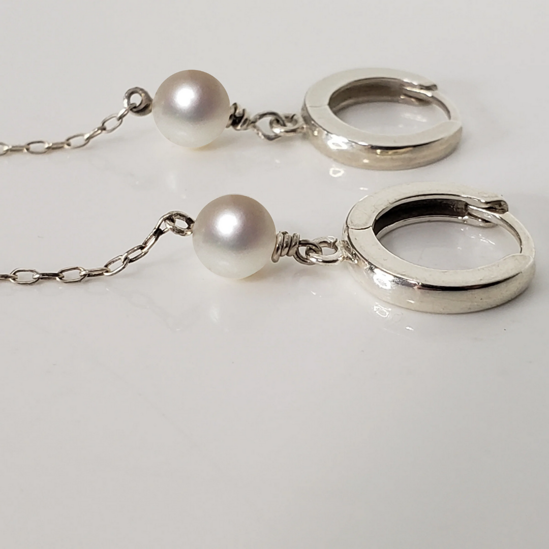 Sterling silver hoop earrings with pearl drop against white background 