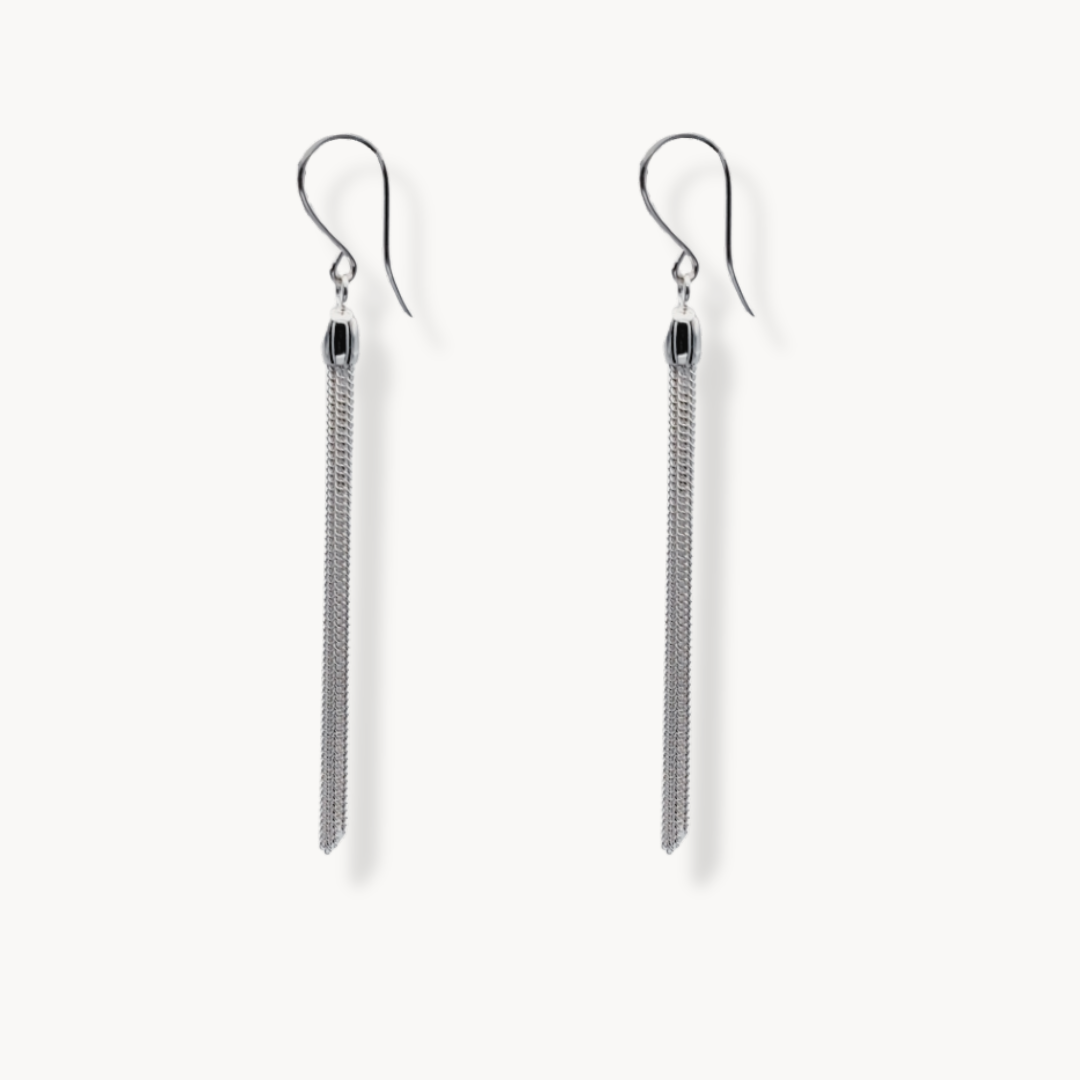 Long silver tassle earrings against beige background