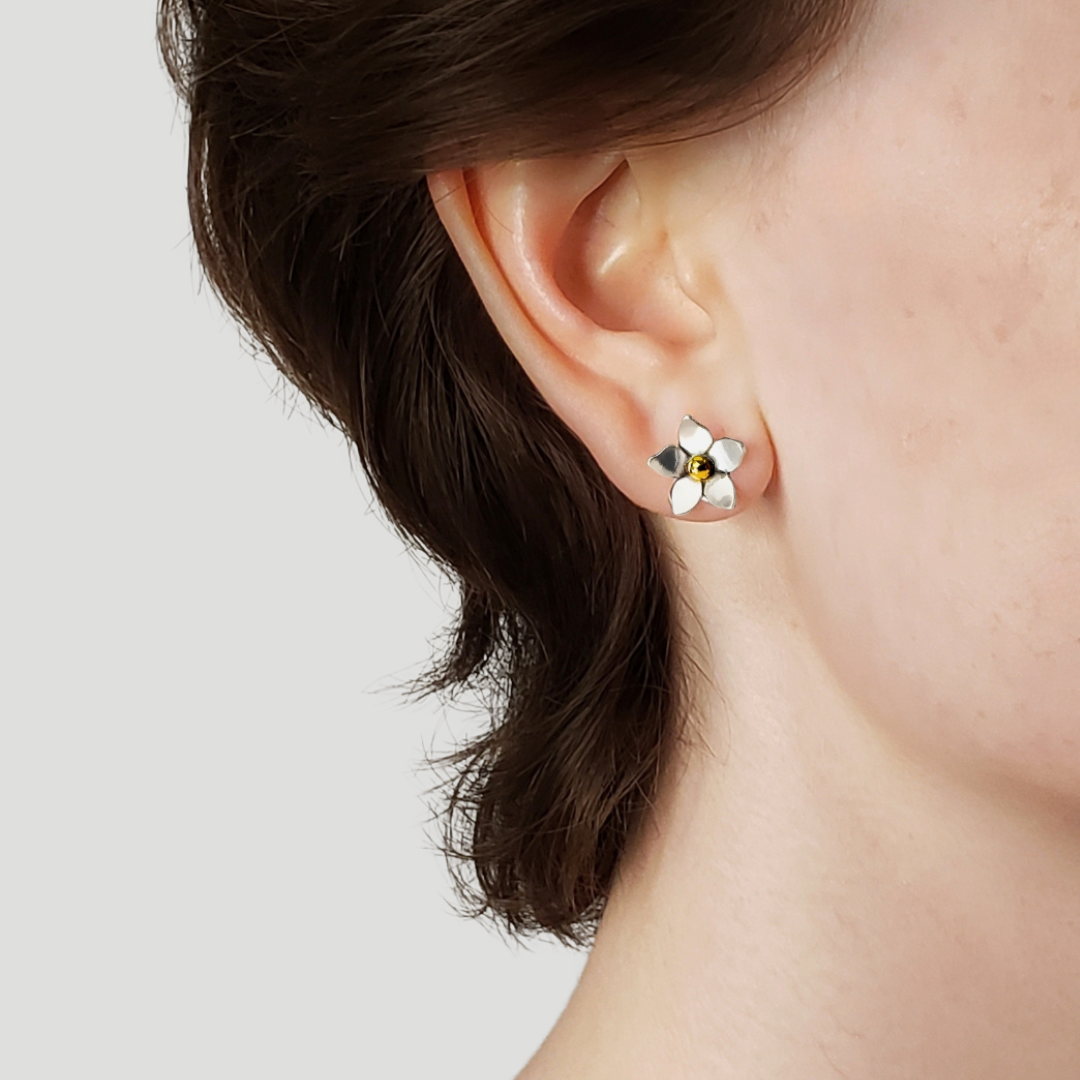 Right facing woman wearing small silver flower earrings