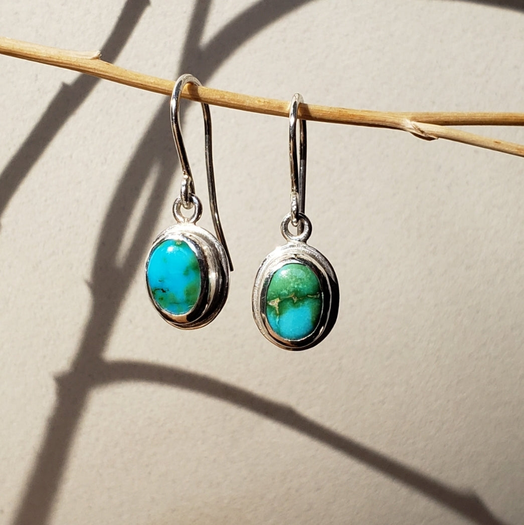 Turquoise drop earrings against a beige background