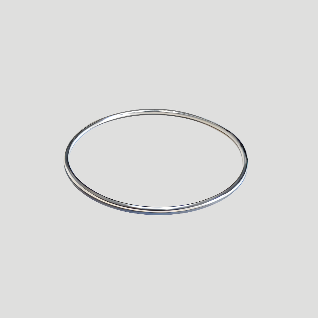 Image of shiny silver bangle bracelet on a beige surface