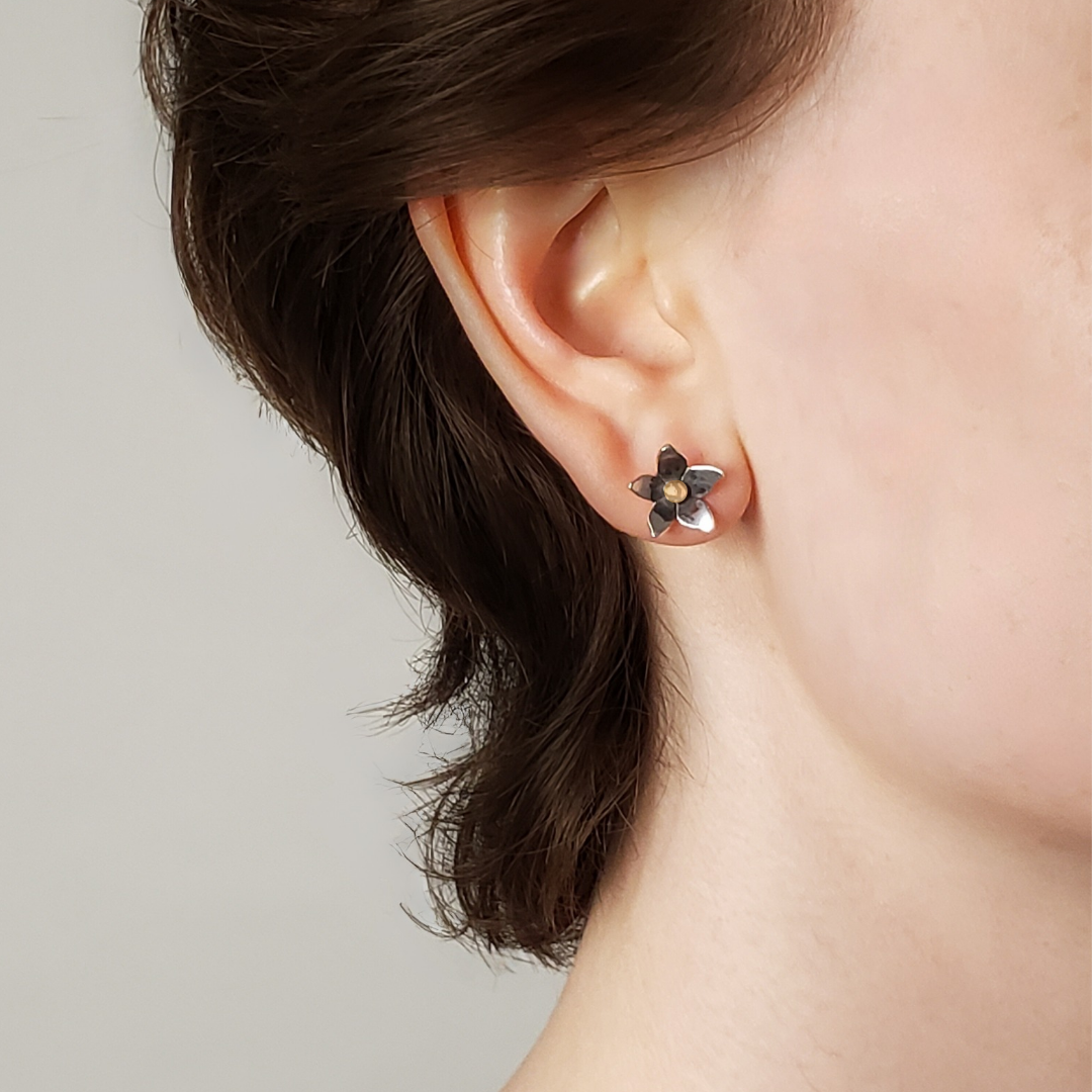 Right facing woman wearing small silver flower earrings