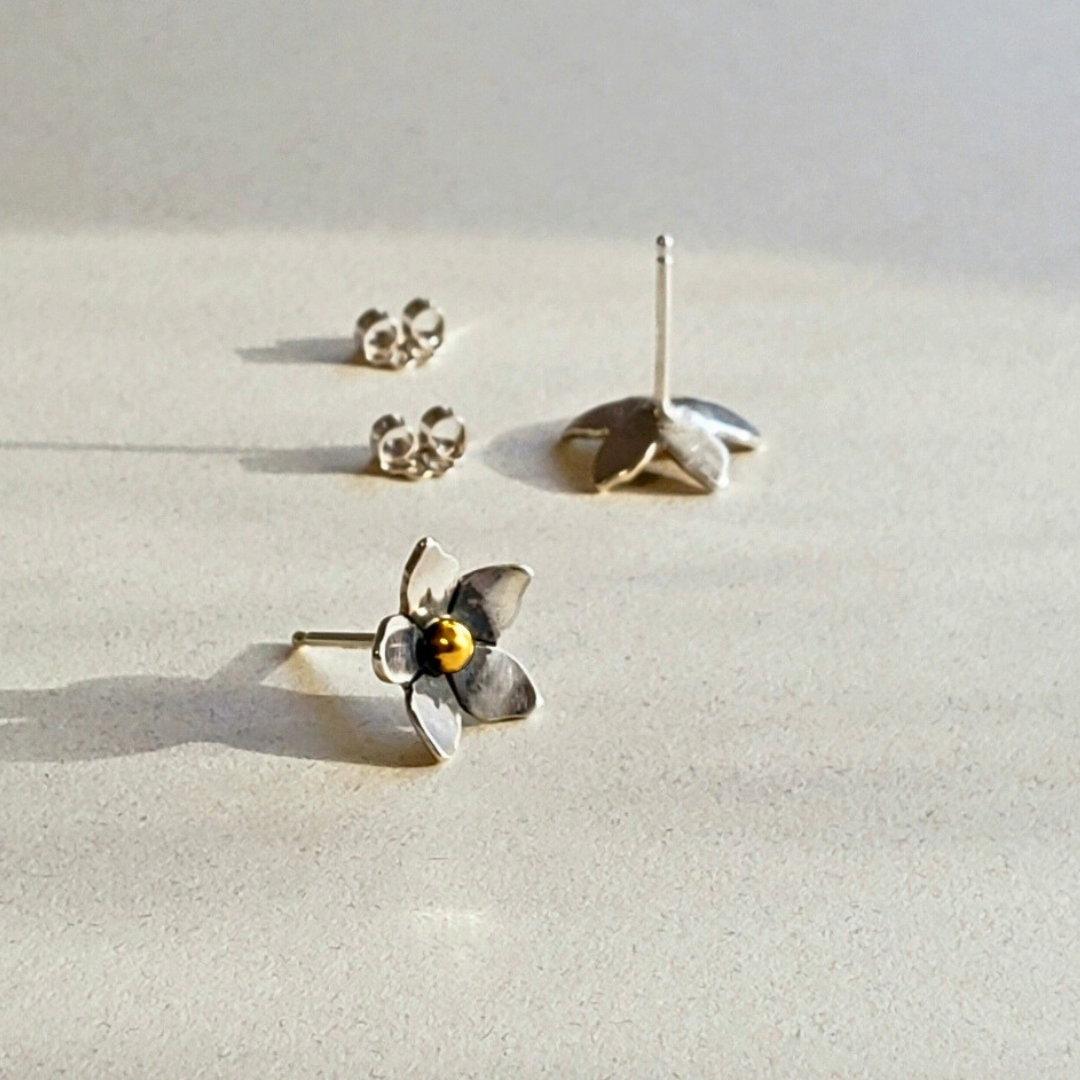 Silver flower stud earrings on beige background 